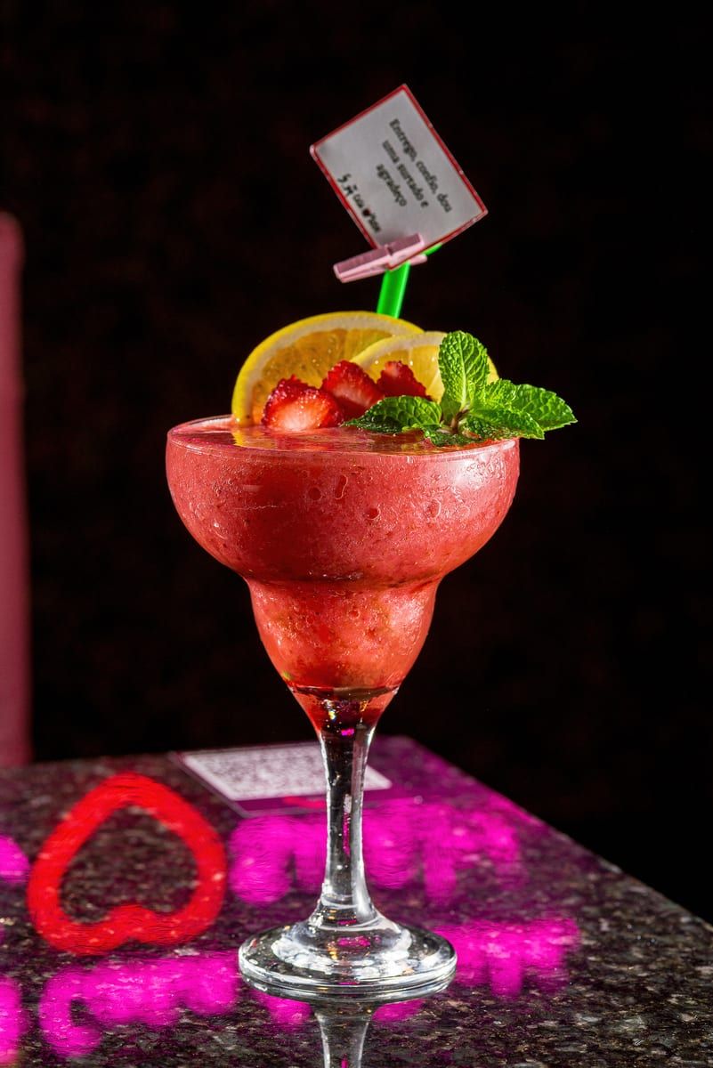Taça de frozen vermelho com morango, rodela de limão e hortelã na borda