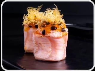 Um joy enrolado em salmão com molho de maracujá e crispy dourado por cima, sobre fundo preto