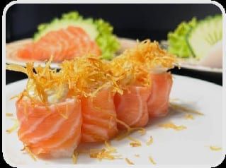 Dois joys enrolados em salmão cobertos por crispy alaranjado de batata-doce, com sashimi ao fundo