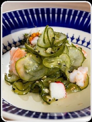 Pepino marinado com pedaços de kani e camarão, em prato de borda azul