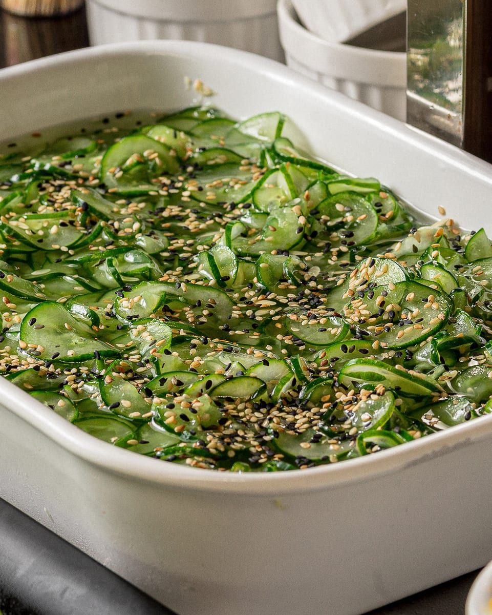 Cuba branca do buffet com lâminas finas de pepino no molho claro, salpicadas de gergelim branco e preto