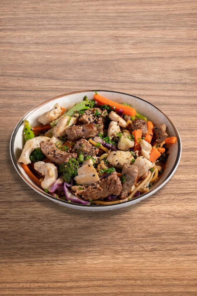 Yakissoba com tiras de carne, legumes e cebola, em bowl de metal